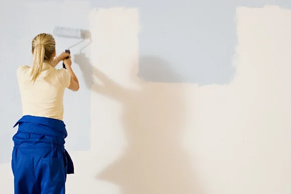 Zwei Personen streichen Wand mit Farbrolle